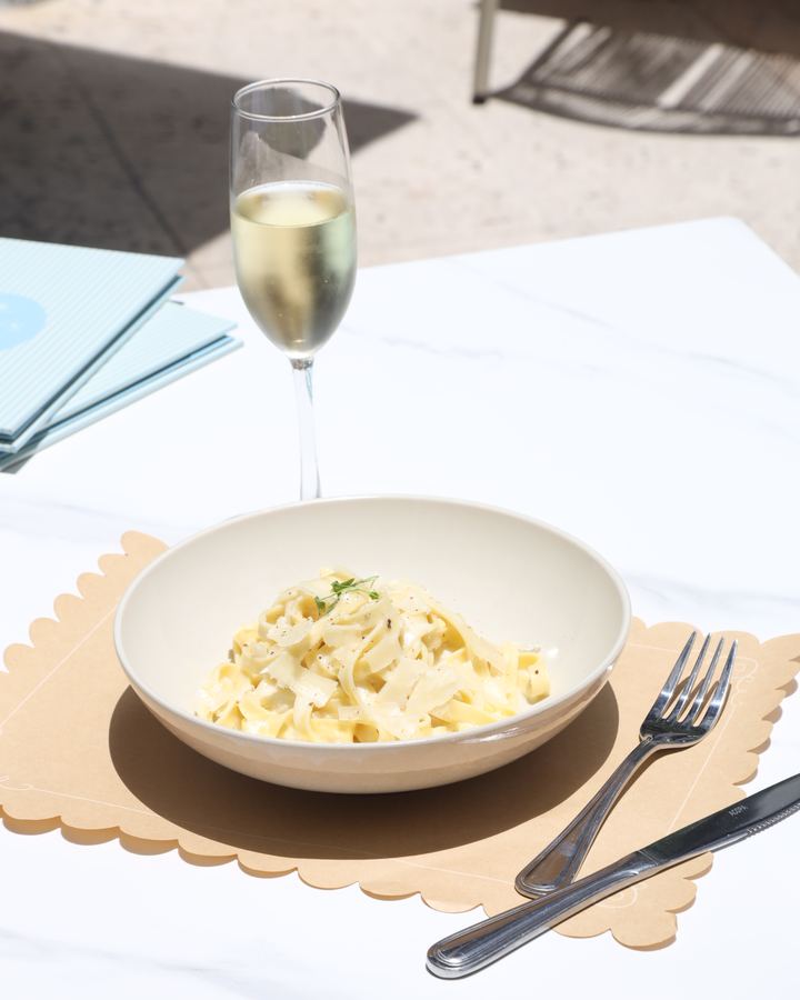 a bowl of pasta with a glass of sparkling wine