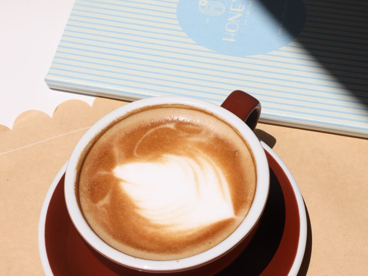 un capuchino con arte latte junto a la carta de Honey's