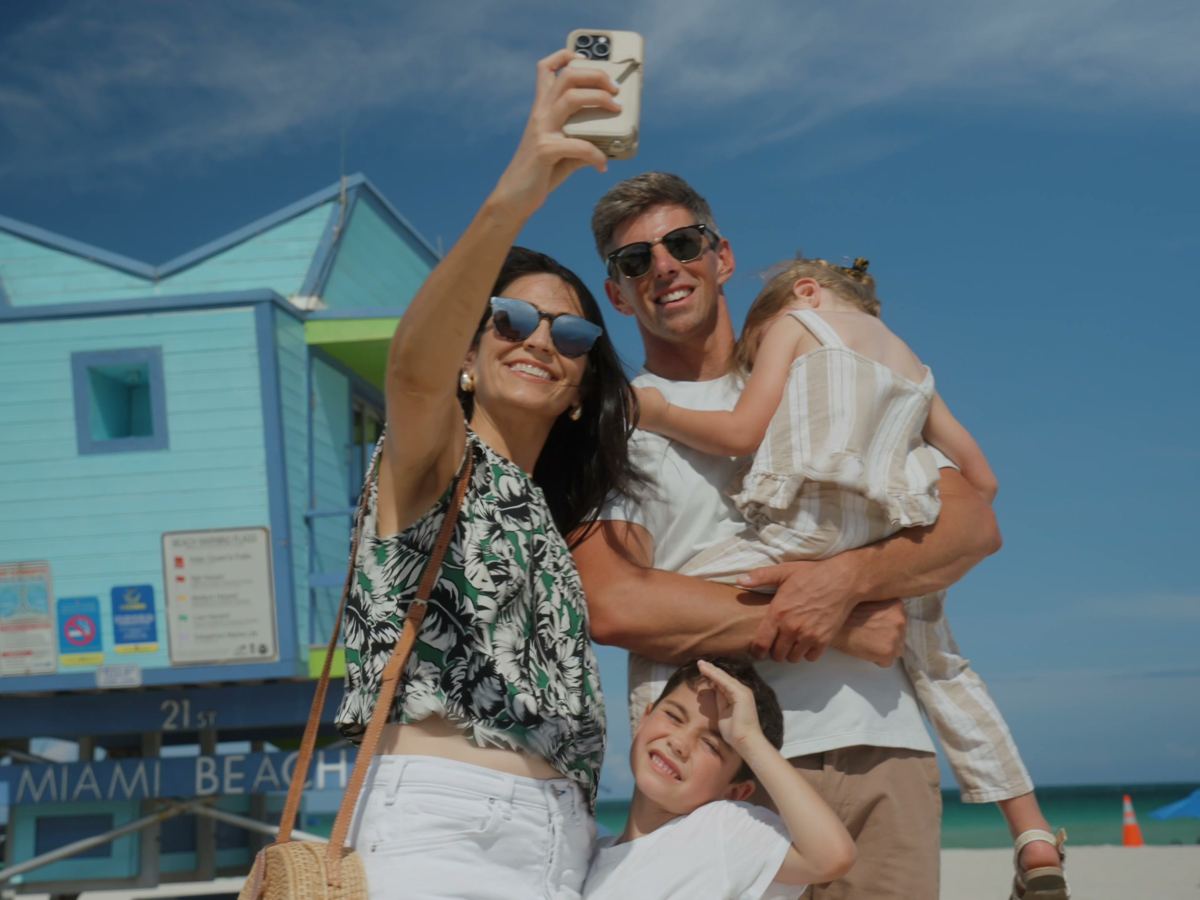 una familia haciéndose un selfie junto a una torre de socorrista en Miami Beach